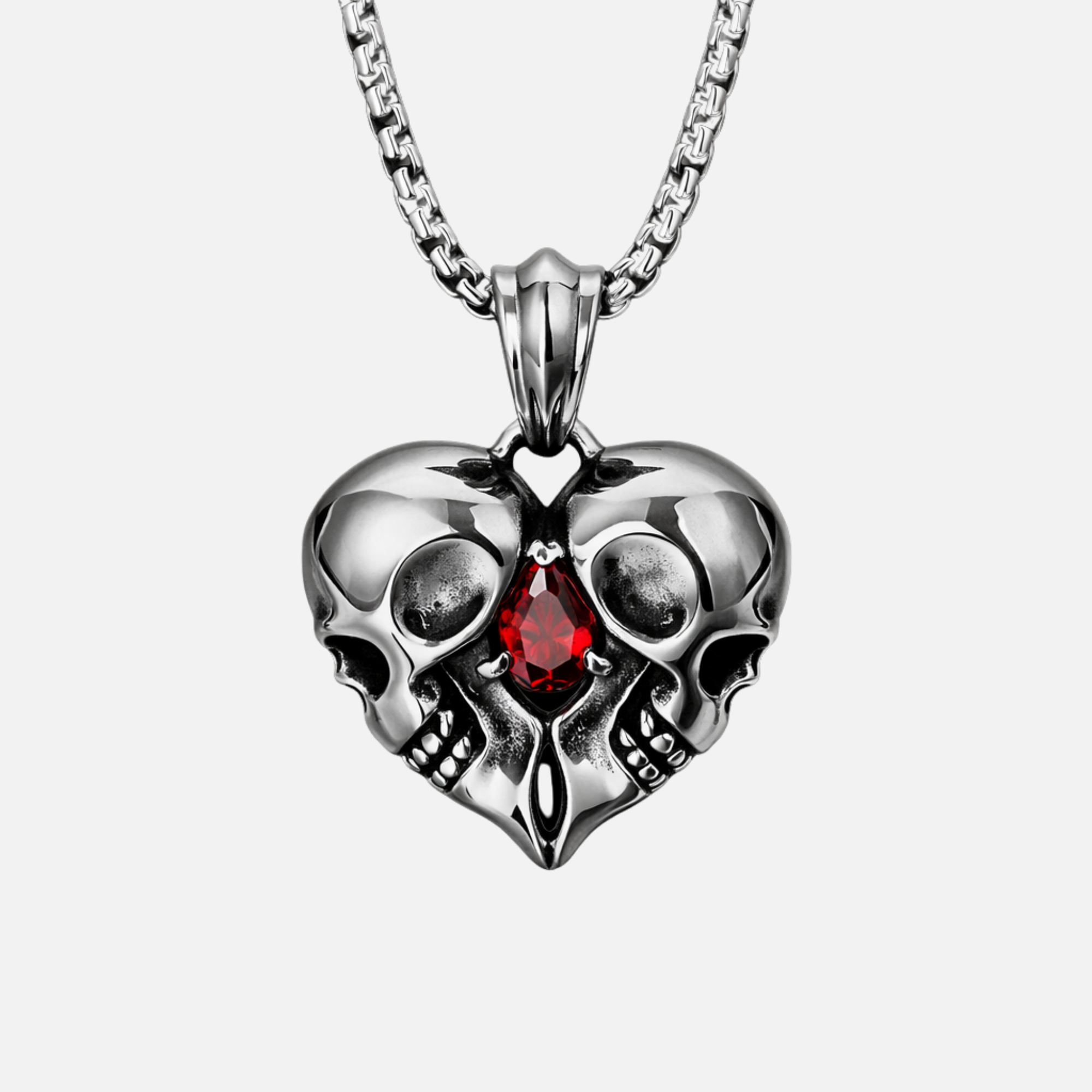Memento gothic skull heart pendant with two interlocking skulls, red zirconia teardrop stone, and polished stainless steel finish
